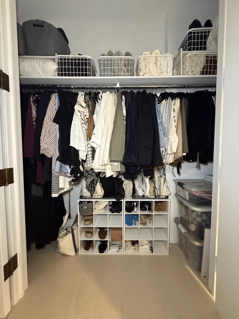 A closet organized by ORG NYC, with clothes hung by type and bins below