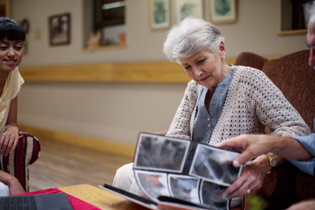 Seniors at a retirement home looking at photo albums, sharing memories and emotional connections, emphasizing compassionate end-of-life planning services.