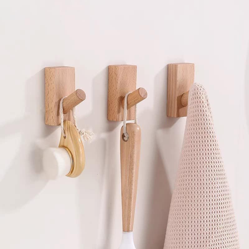 Wooden wall hooks with a natural finish, designed for space-saving organization in small NYC apartments, displaying a rolling pin and a towel.