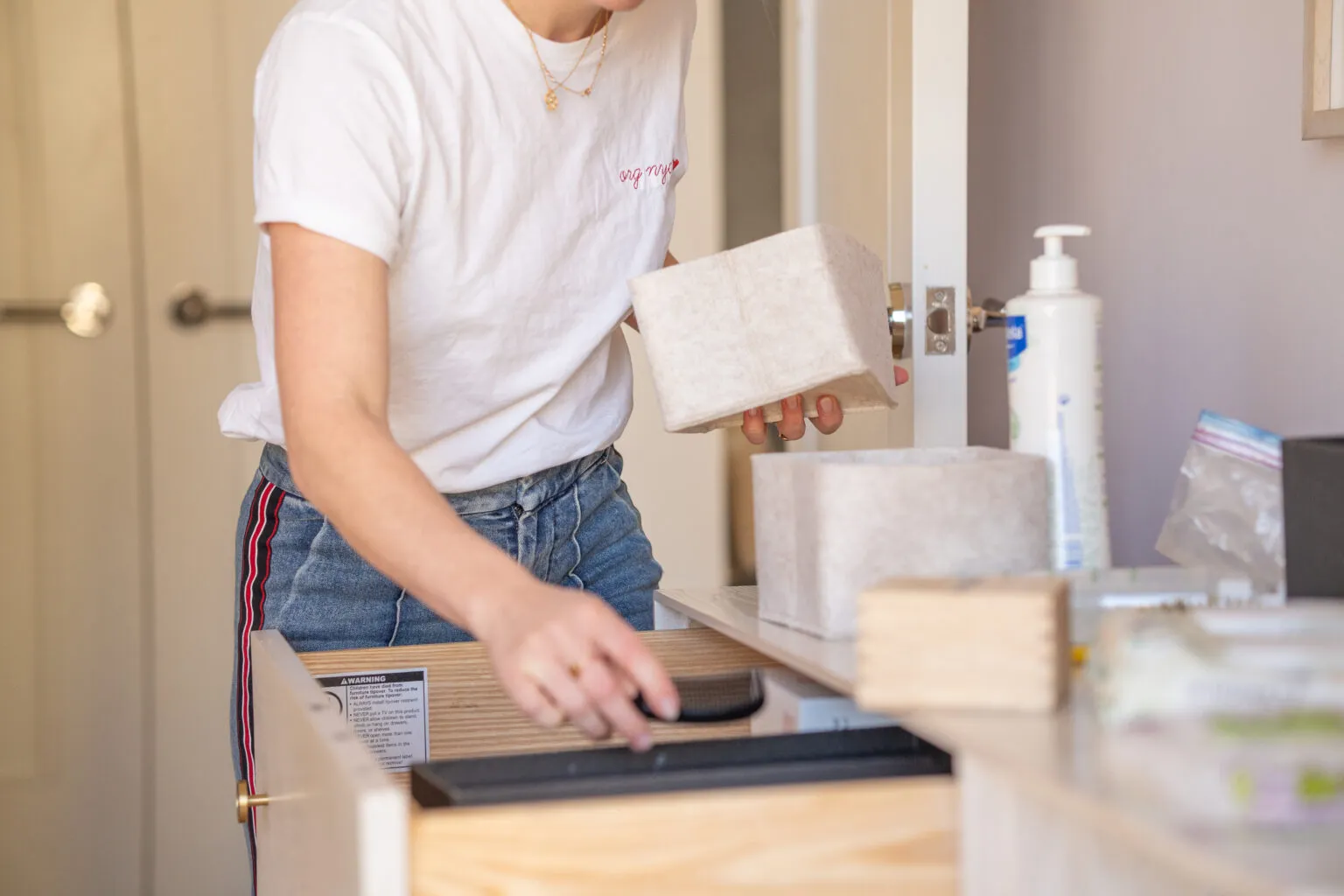 An ORG NYC organizer in a branded tee sorting items into containers during a one-space reset