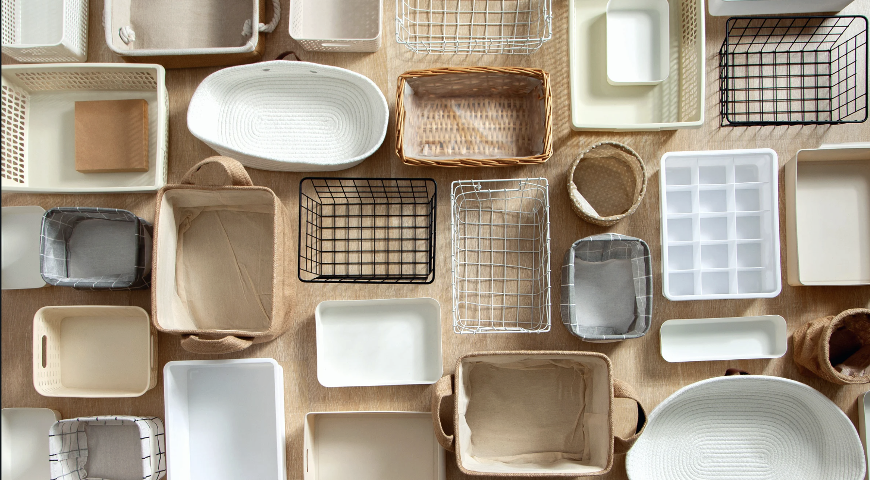 Assorted storage containers and baskets on a wood surface. Home organization concepts for finding the right personal organizer in New York, NY.