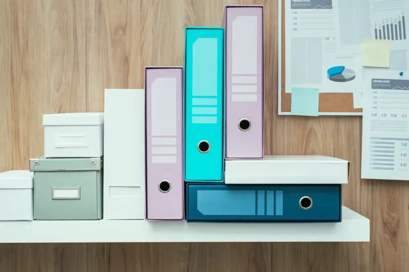 Colorful ring binders and storage boxes neatly arranged on a white shelf help ensure your home stays organized and efficient