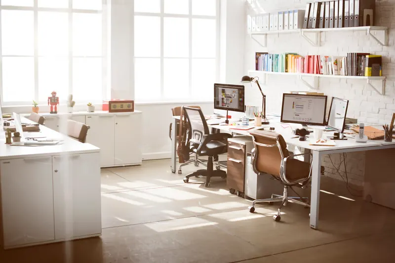 Bright office with wall mounted floating shelves and organized desks representing shared office storage in New York, NY workspace