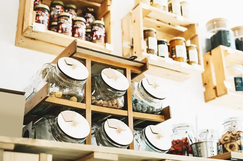 Glass storage jars with white lids sorted on wooden pantry shelves in an organized kitchen